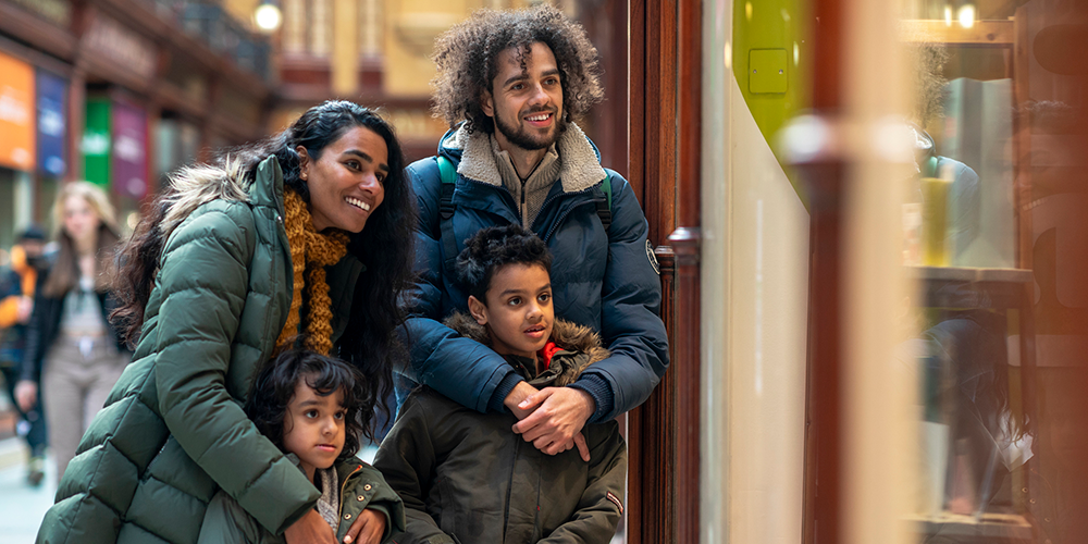 A family of four window shopping on a sunny winter day.
